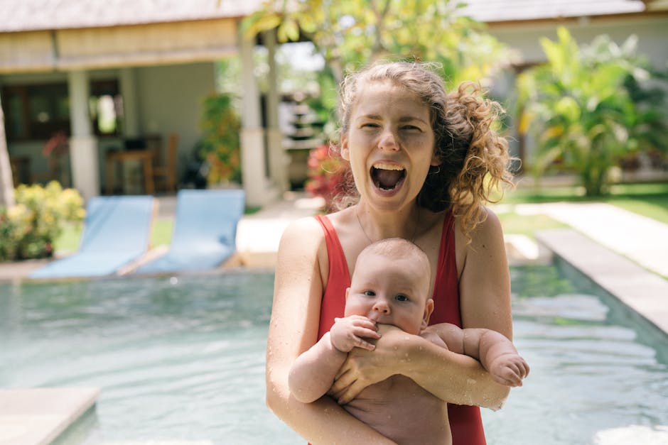 Mother and baby enjoying a sunny day by the pool with laughter and joy.