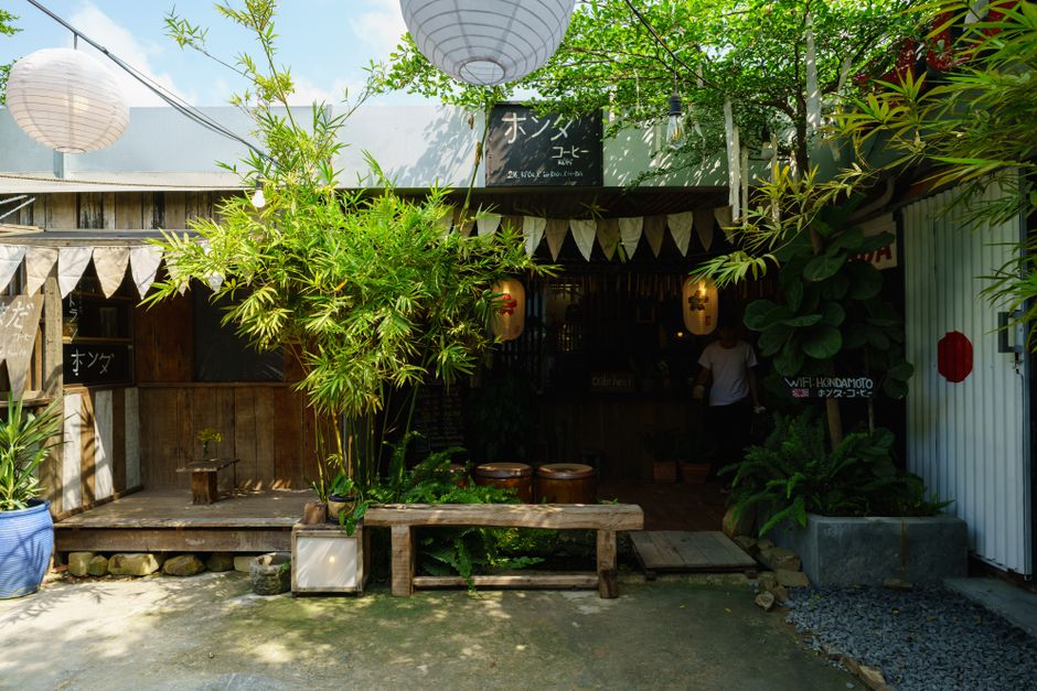 Rustic outdoor cafe adorned with bamboo plants, wooden decor, and cultural lanterns.