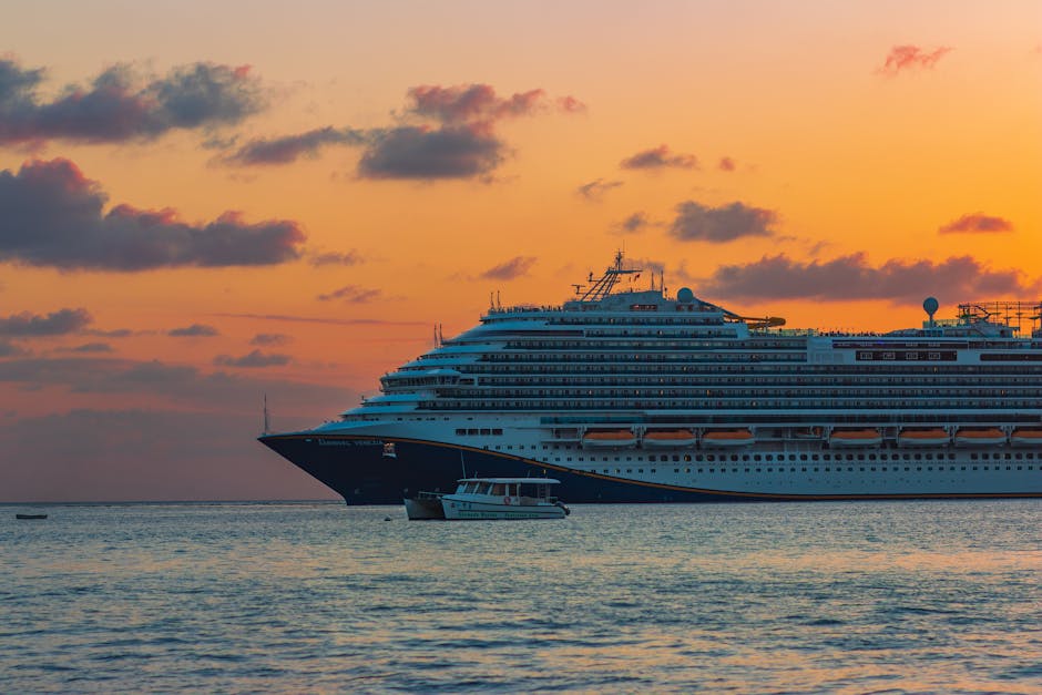 A majestic cruise ship sails across calm seas during a stunning sunset, silhouetted against a vibrant sky.