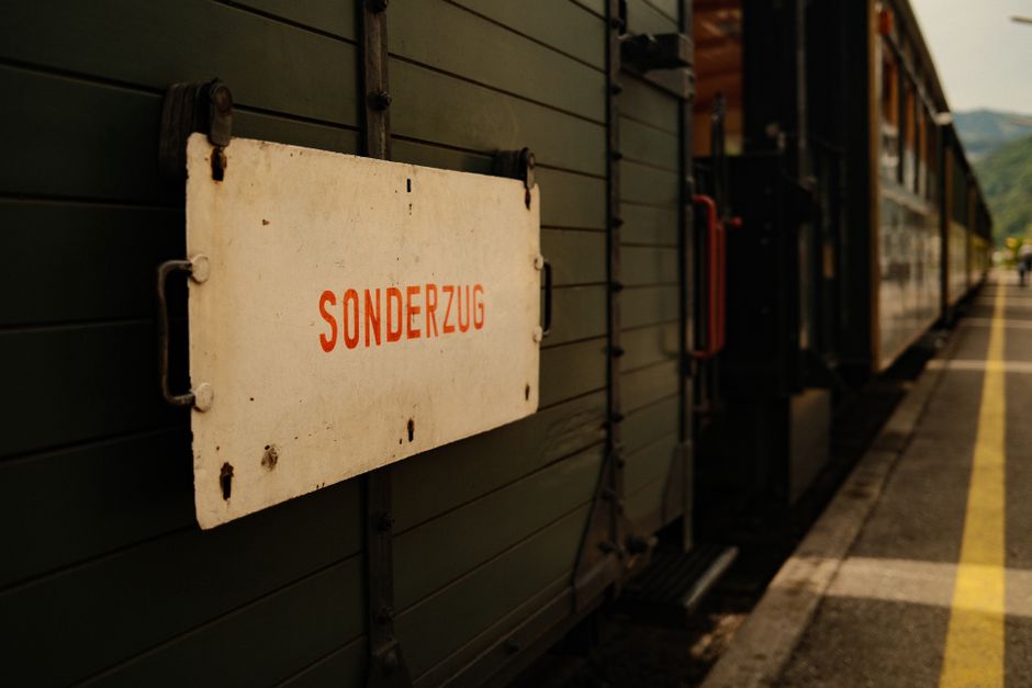 Close-up of a historic train with a 'Sonderzug' sign at a sunny outdoor station platform.