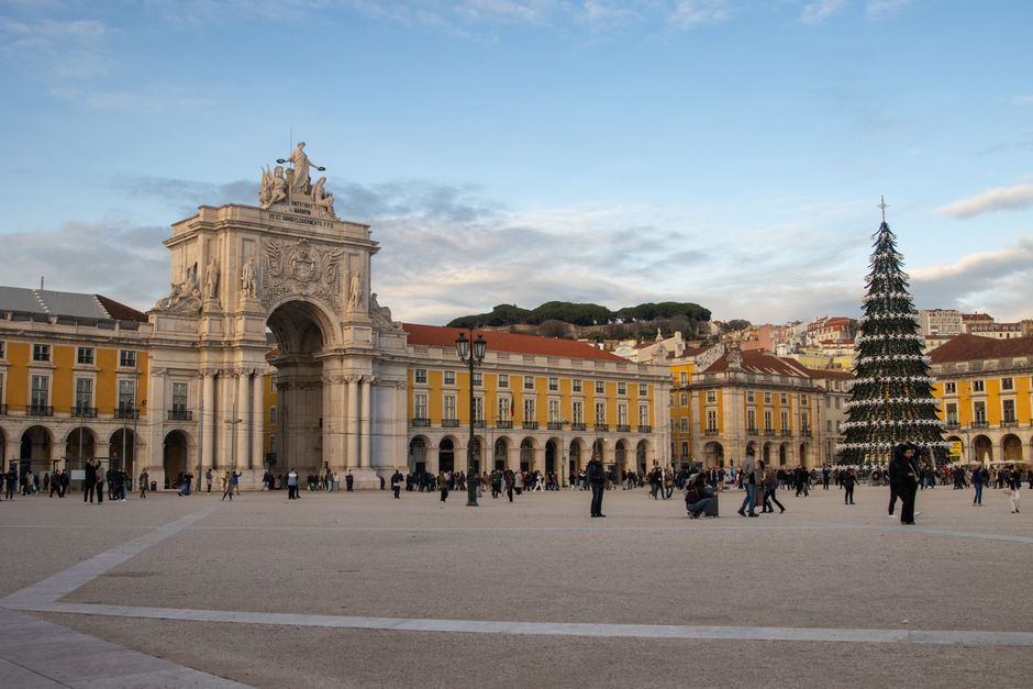View of Lisbon's iconic Praça do Comércio with a festive Christmas tree and Arc de Triomphe.