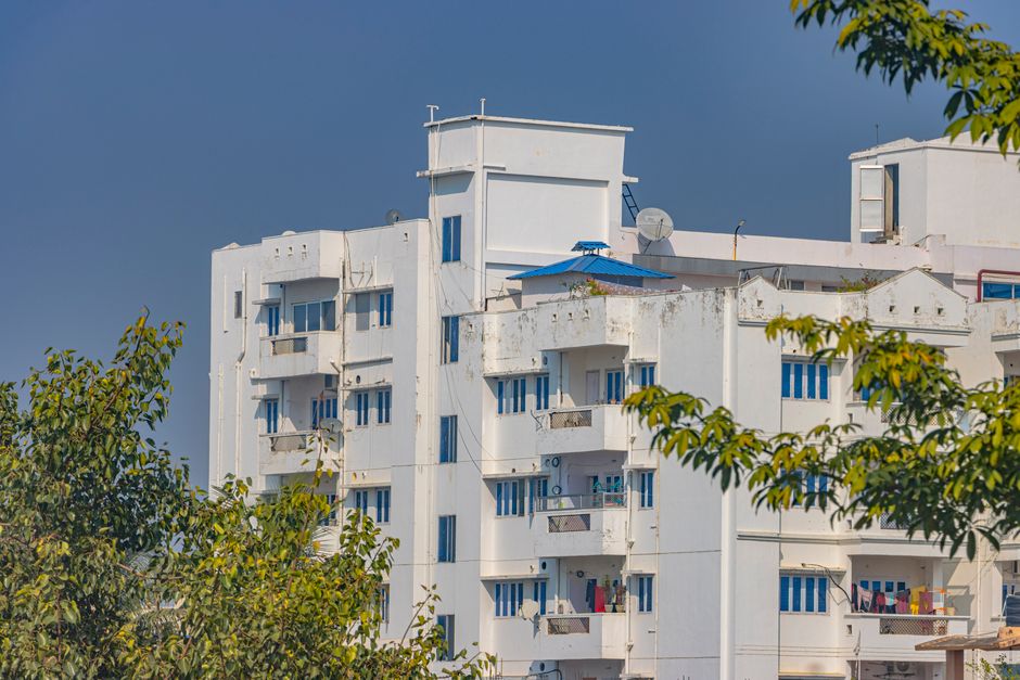 A modern white residential building with vibrant blue windows in Hazaribagh, Jharkhand, India.