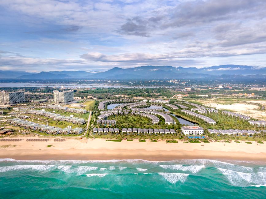 Stunning aerial view of a beachside resort with palm trees and modern architecture.