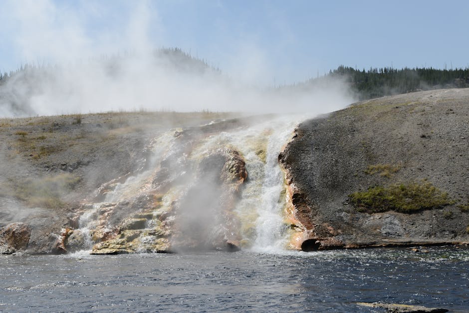 A scenic view of steaming hot springs and waterfall in Yellowstone National Park.