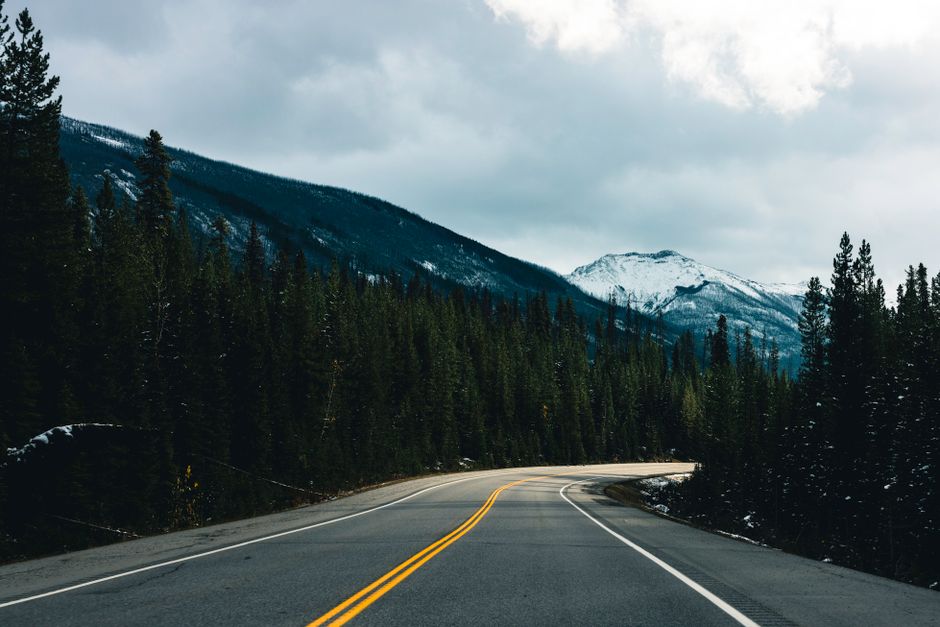 Curving road through Kootenay National Park with forest and mountain views.