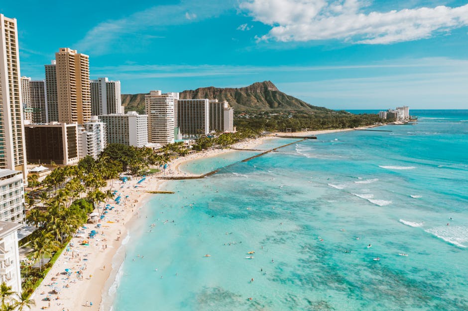 Aerial shot of Waikiki Beach with high-rises and Diamond Head under a blue sky.